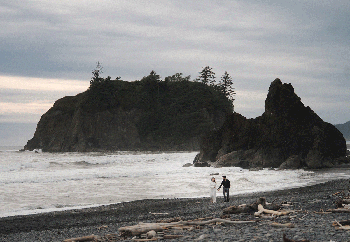 A person walks along Ruby Beach near dramatic sea stacks and evergreen trees in Olympic National Park, Washington.