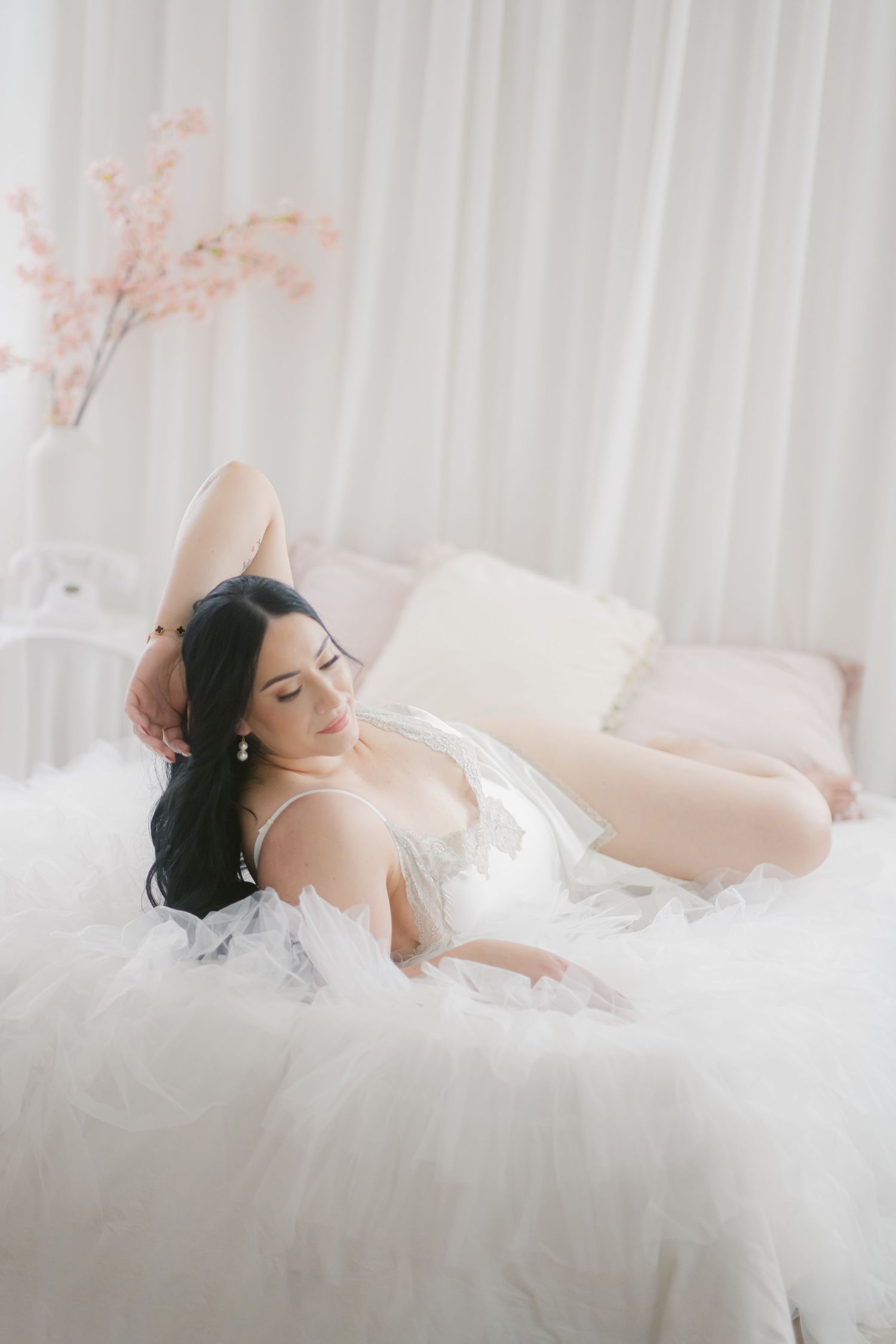 Ethereal boudoir photo with soft white tulle and delicate blush florals creating a dreamy, romantic atmosphere.