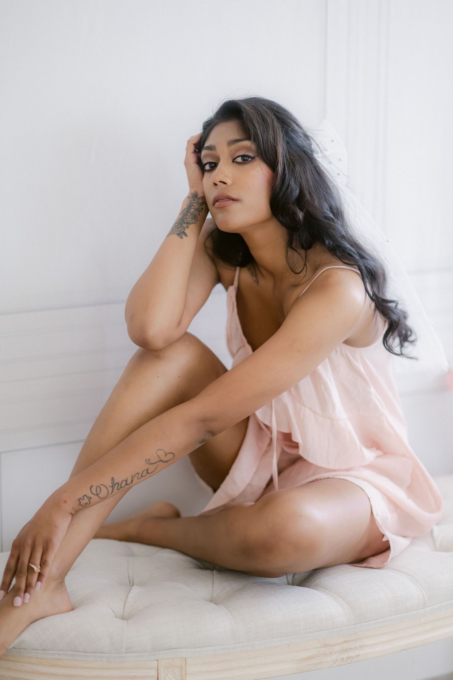 Artistic boudoir portrait in soft pink featuring delicate fabrics and natural light.