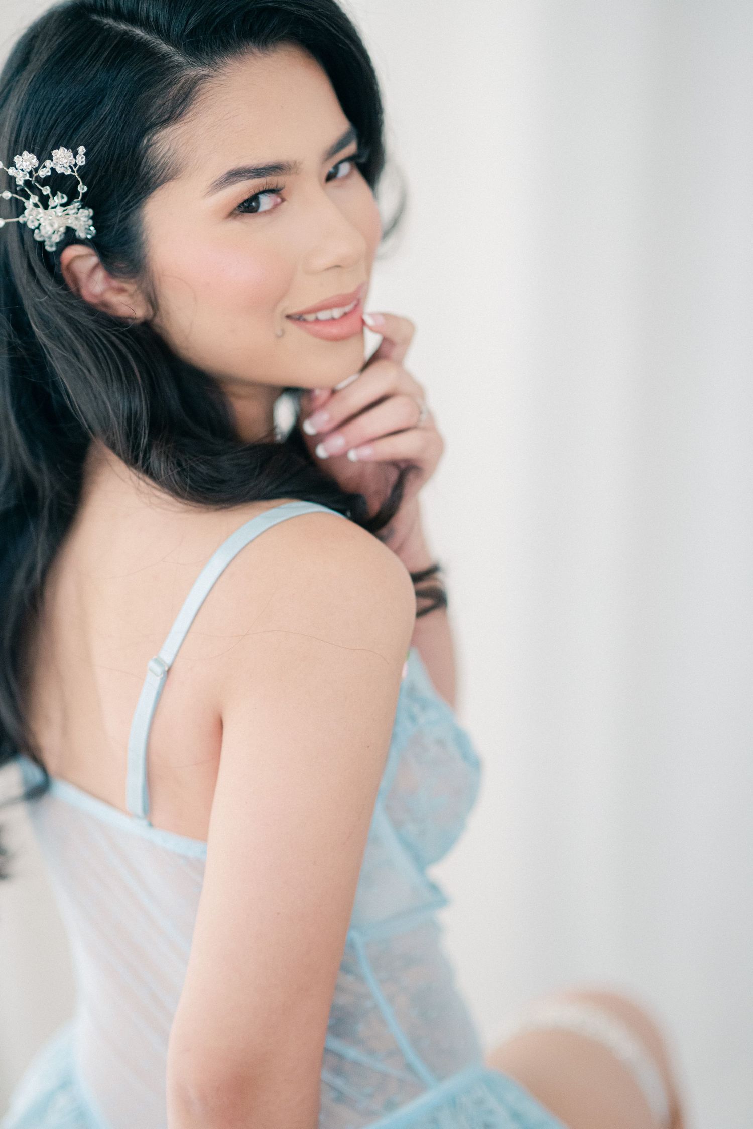 Romantic portrait featuring delicate floral hair accessories and powder blue lingerie in soft natural lighting.