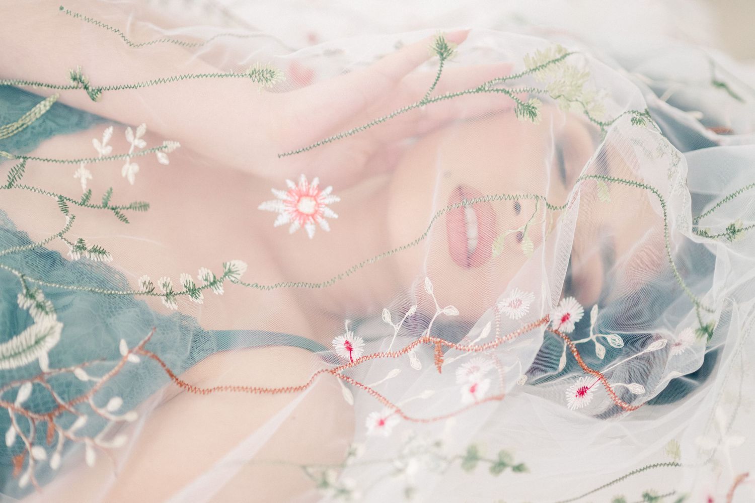 Ethereal macro photograph of pastel pink and mint floral fabric with delicate embroidered details.