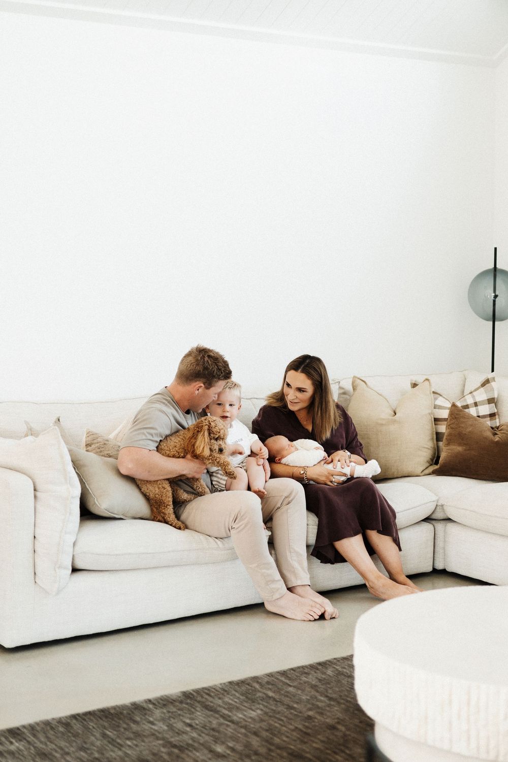 Family relaxing together on large white sectional sofa in bright minimalist living room.