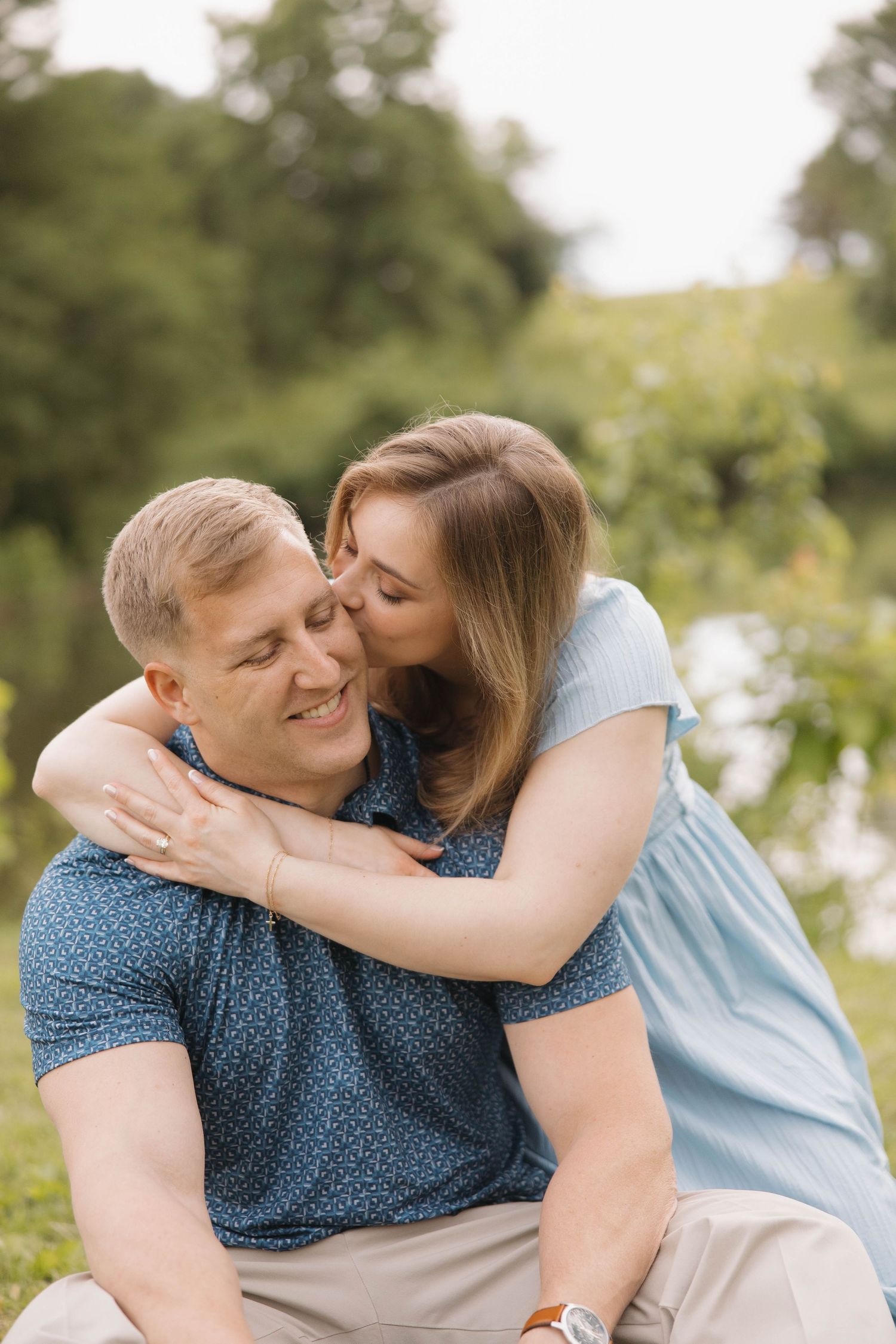 A romantic outdoor photoshoot showing a tender moment between a couple in a natural park setting.