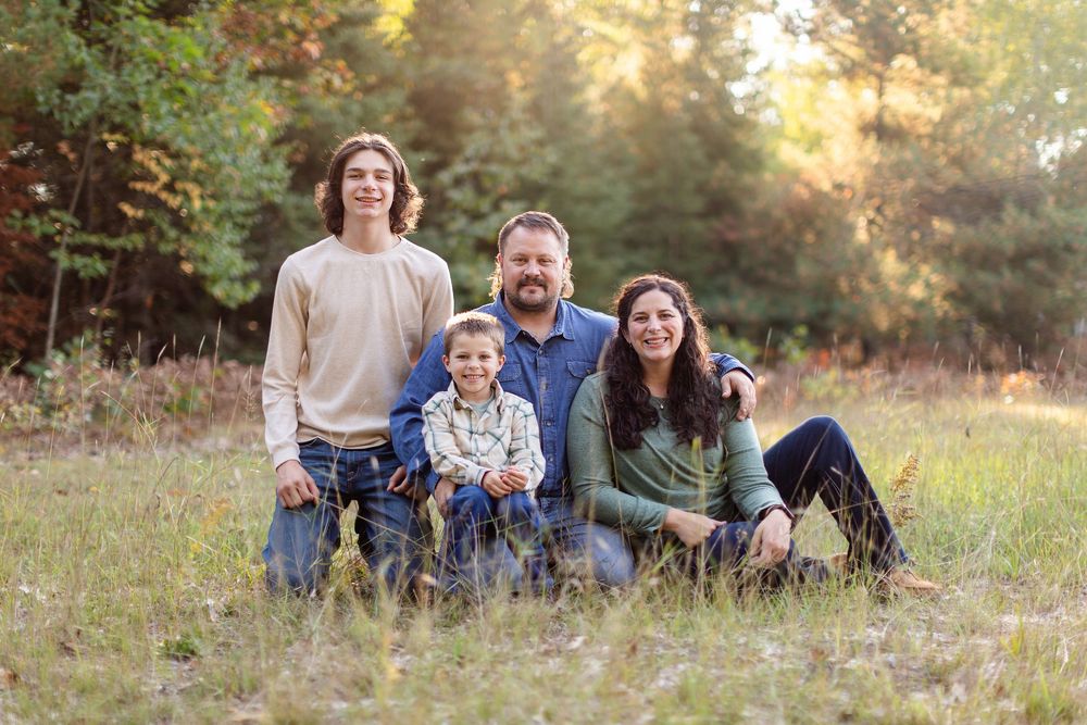A group relaxes together on grass in a natural outdoor setting during golden hour lighting.