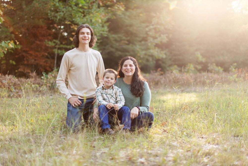 Candid family portrait in a grassy field during golden hour with warm sunlight.
