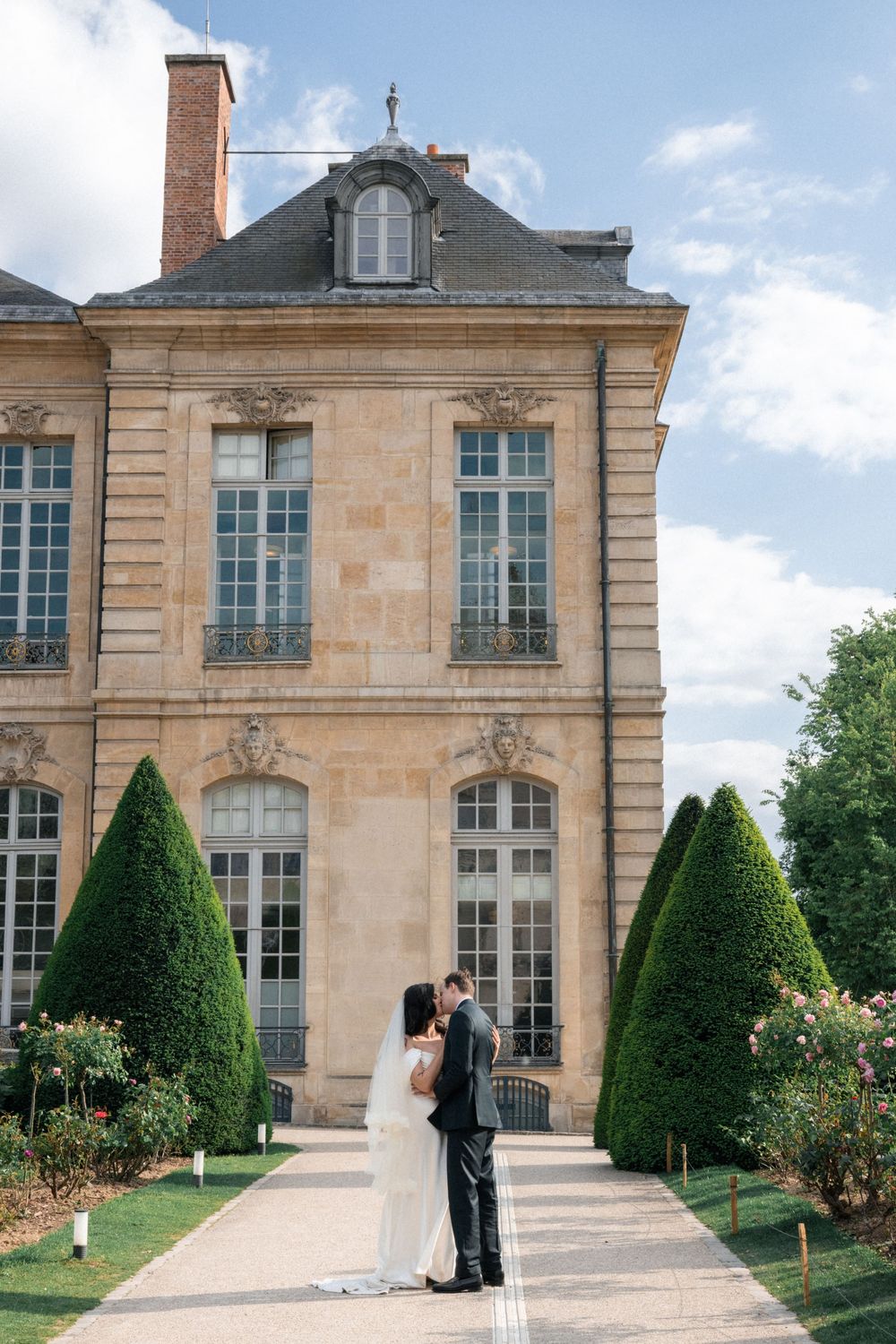 Elegant French chateau exterior with manicured topiary gardens and classical architecture.