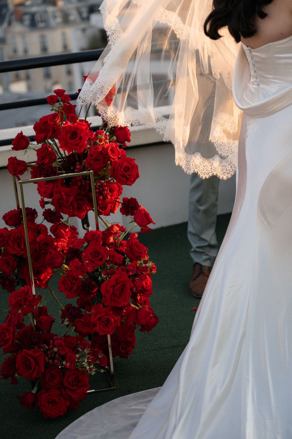 White wedding dress and vibrant red roses on a rooftop terrace overlooking Paris.
