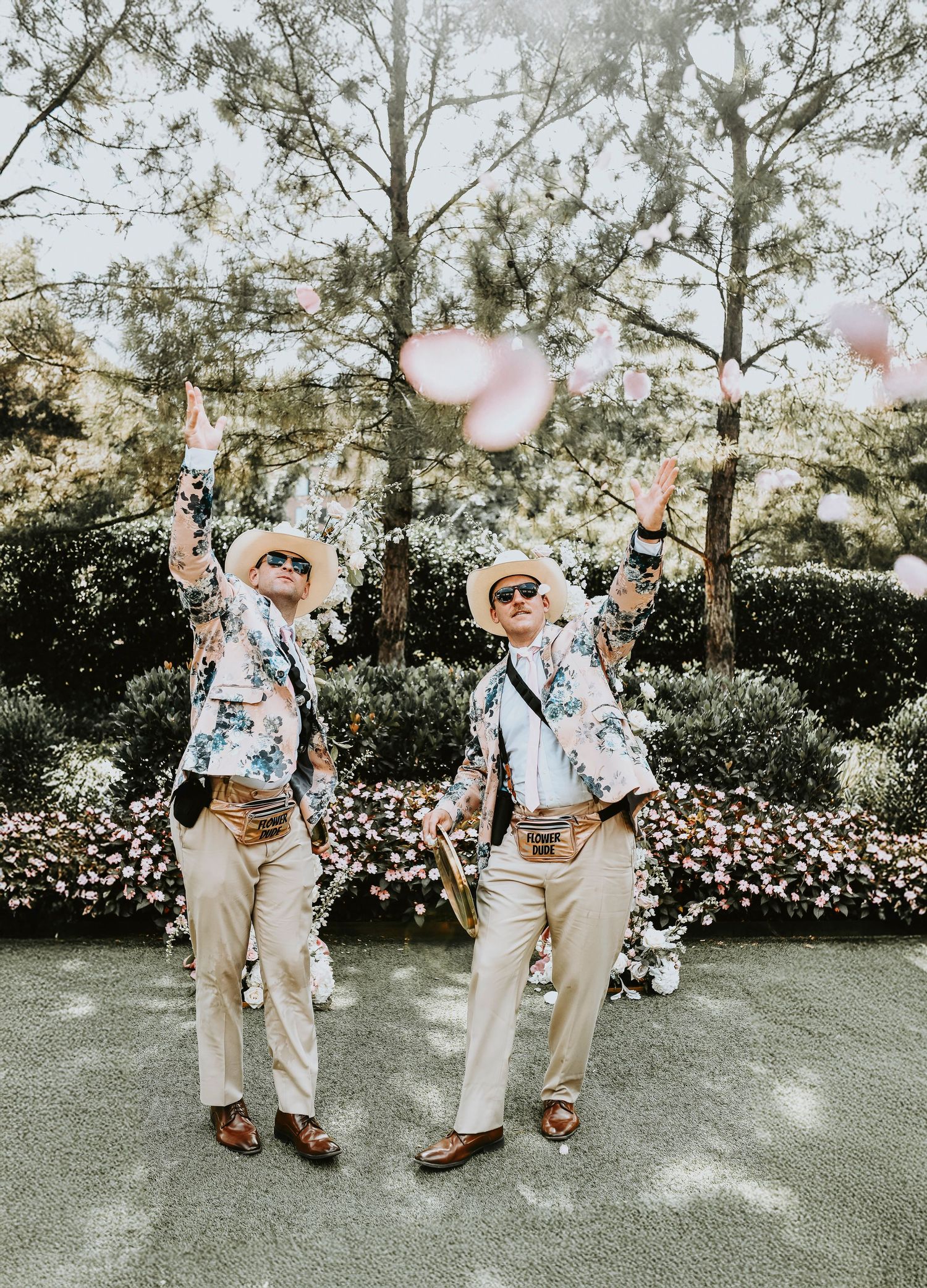 Guests cheering and clapping as flower dudes walk down the aisle tossing pink petals before the bride walks down the aisle