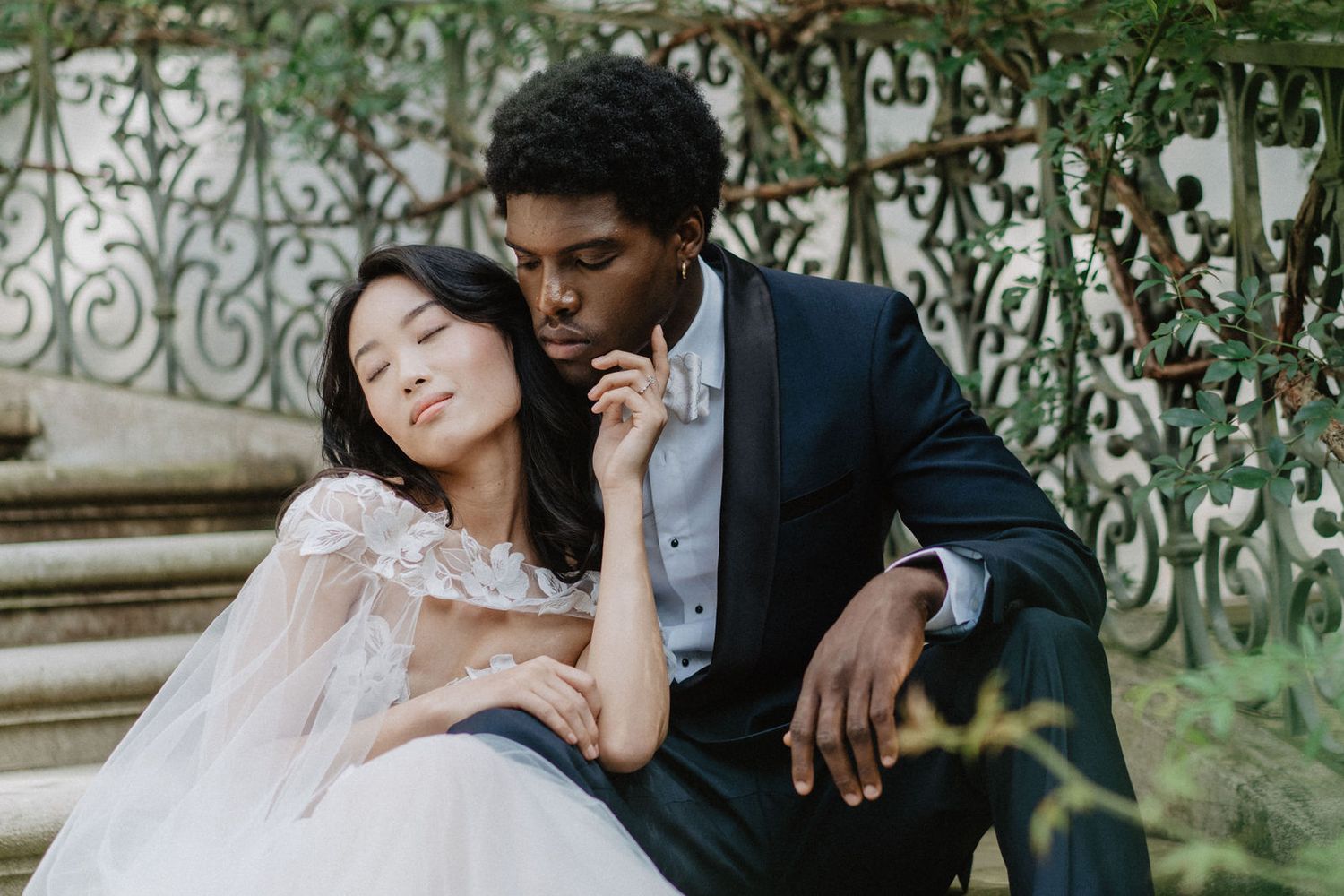 A tender moment captured between a couple in wedding attire on garden steps.