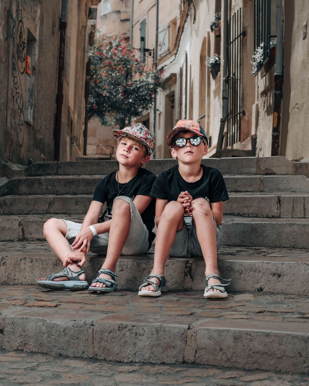 Four sequential shots show a person sitting on stone steps while wearing black shorts and white sneakers.