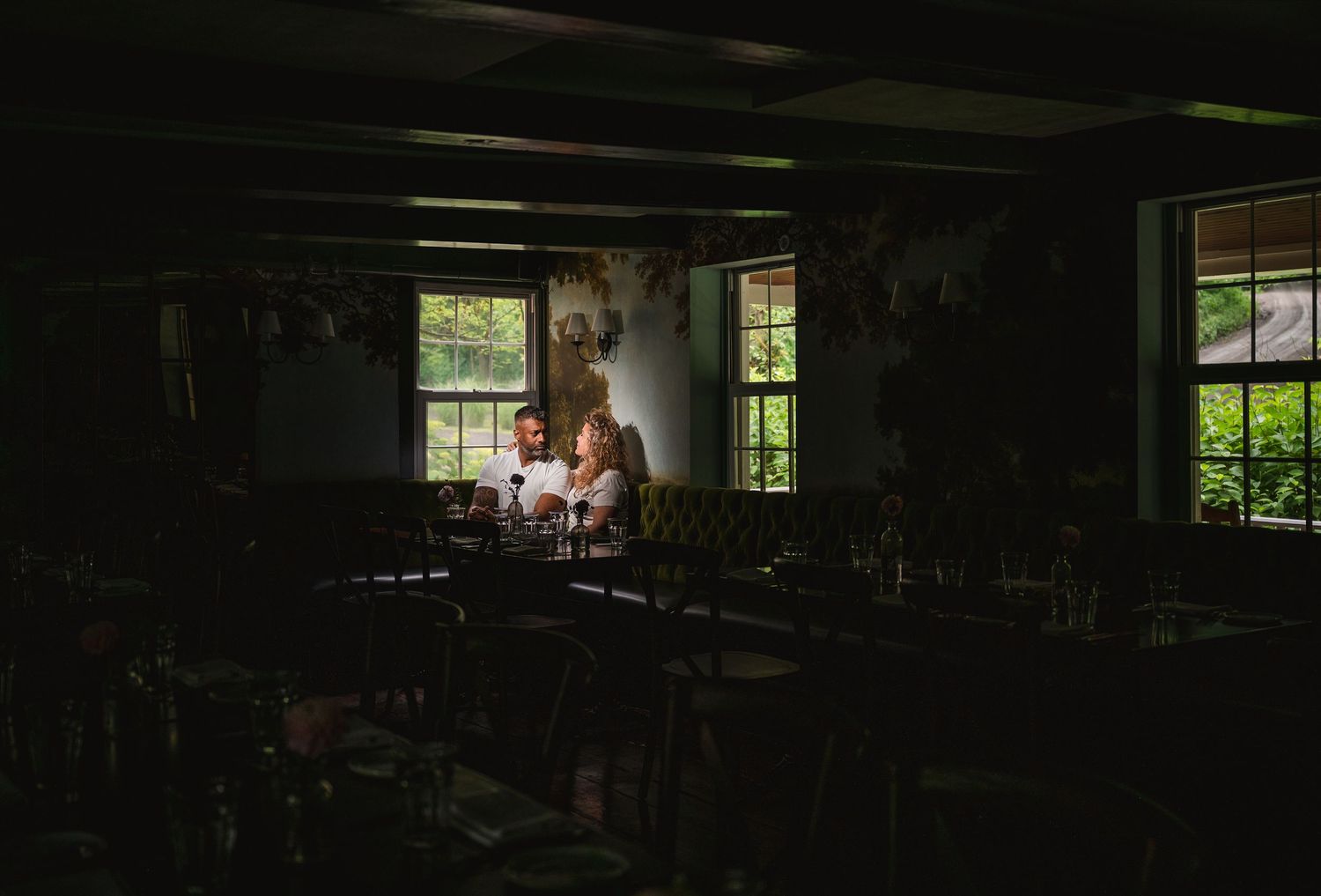A person sits illuminated by candlelight in a dark classroom while working late into the evening.