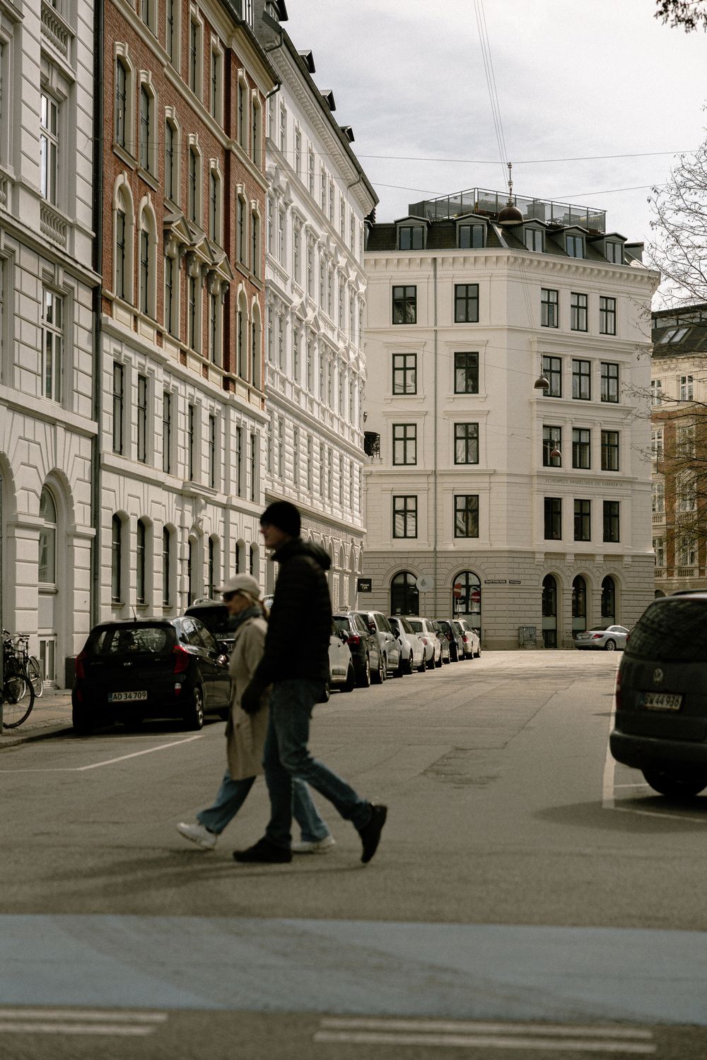 Urban street scene with classic European architecture and parked cars along residential buildings.