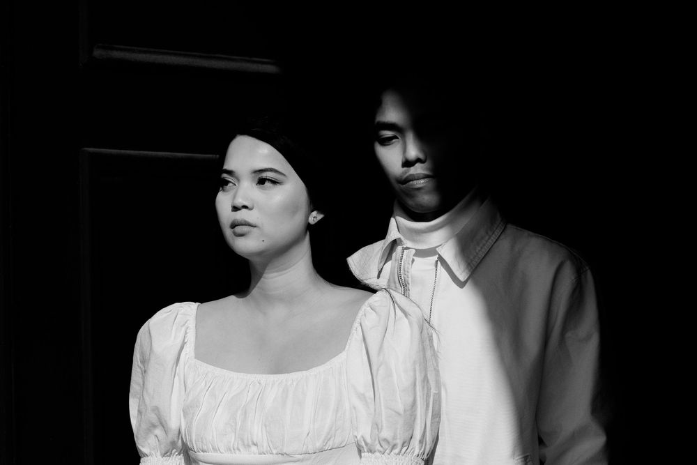 Dramatic black and white portrait of a couple in white clothing against dark background. Destination wedding photographer Copenhagen
