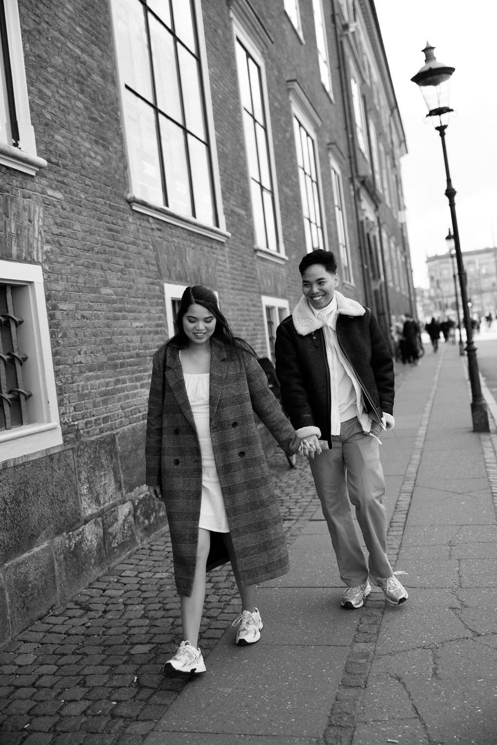 Casual couple walking hand in hand along urban street with historic buildings. Destination wedding photographer Copenhagen