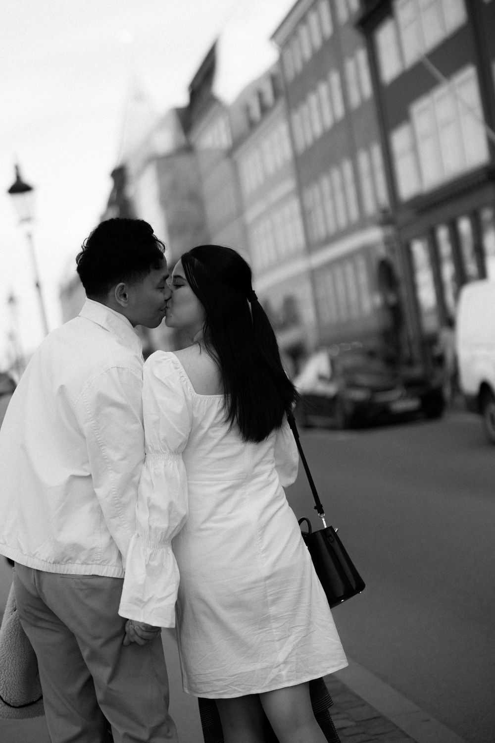 Intimate black and white photo of couple sharing tender moment on city street. Destination wedding photographer Copenhagen