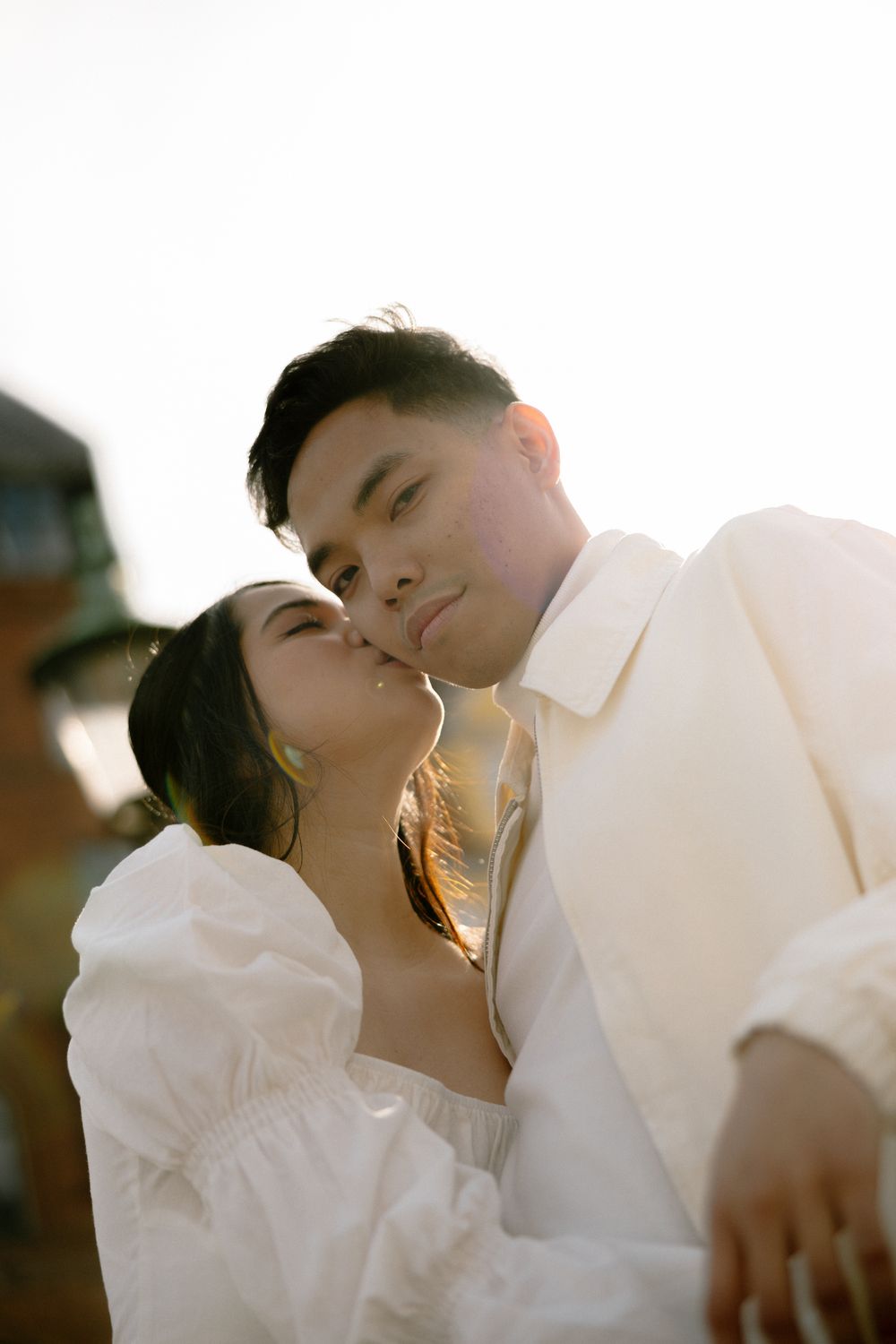 Intimate portrait of couple in white clothing bathed in golden sunlight. Destination wedding photographer Copenhagen
