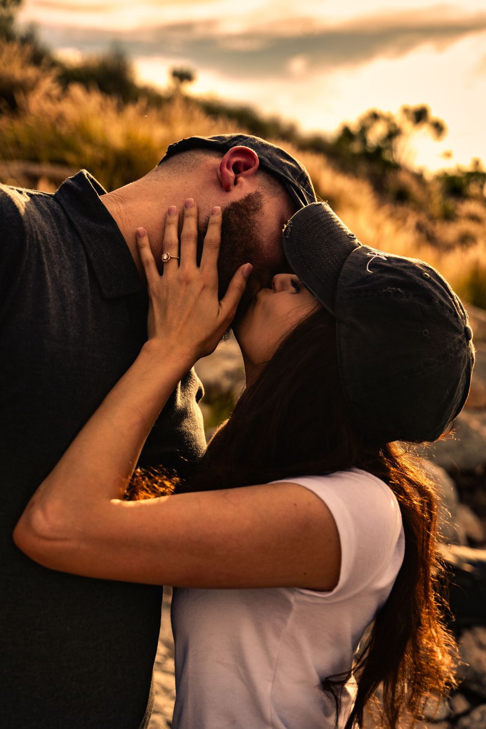 Romantic couple sharing intimate moment at sunset in nature.