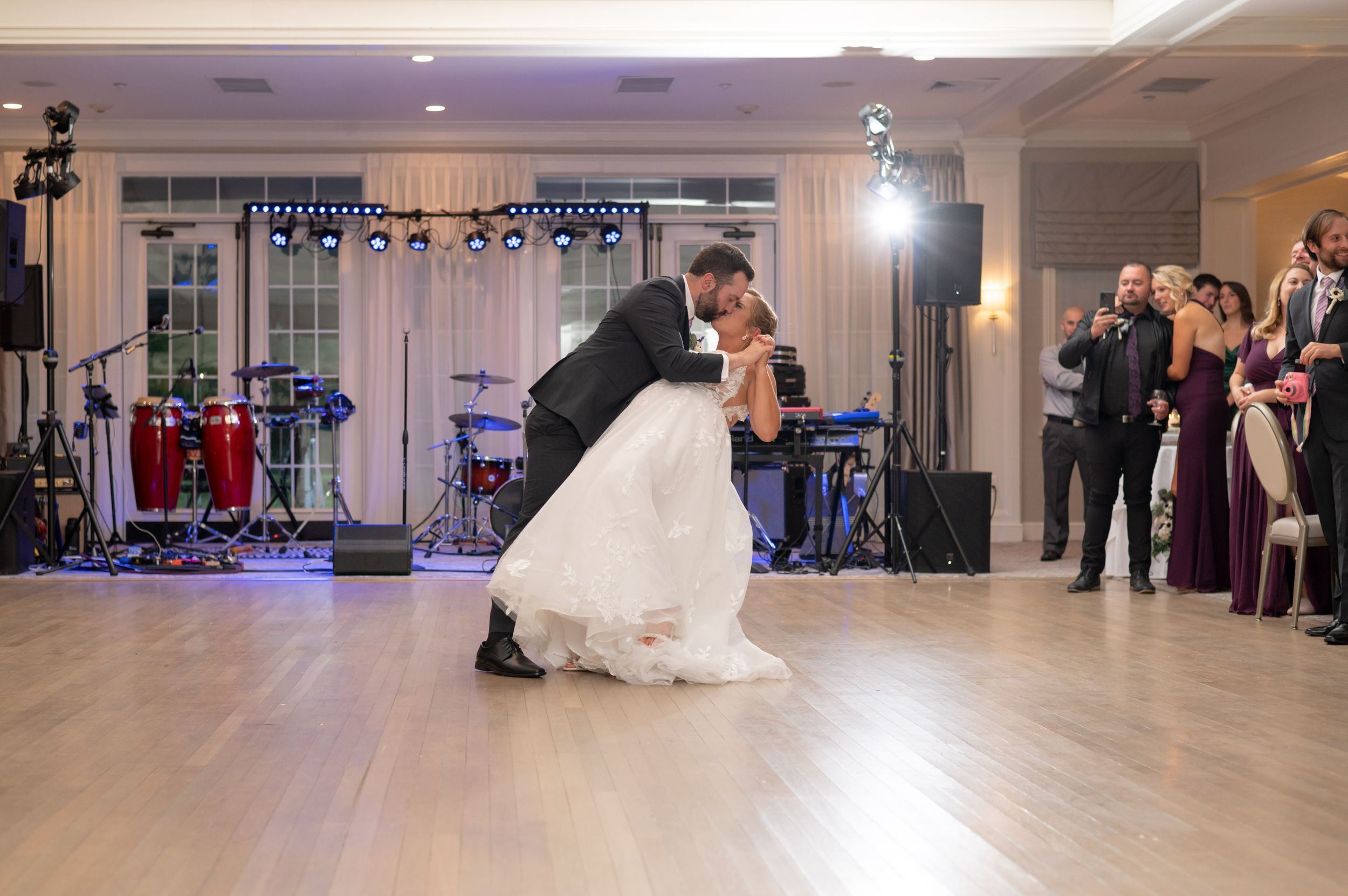 A couple performs their first dance at their wedding reception while wedding guests watch from the sidelines.