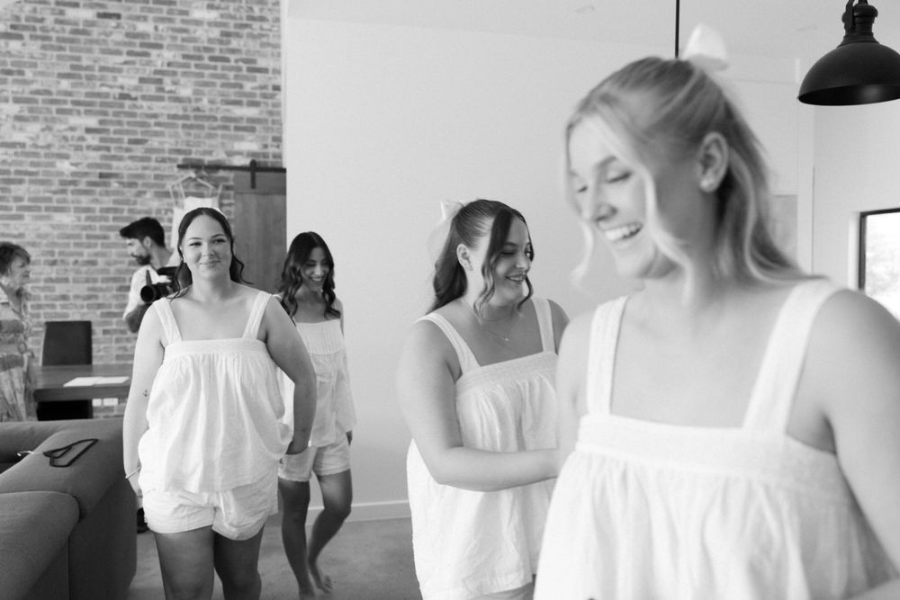 People in white sundresses walking together in a black and white photograph.