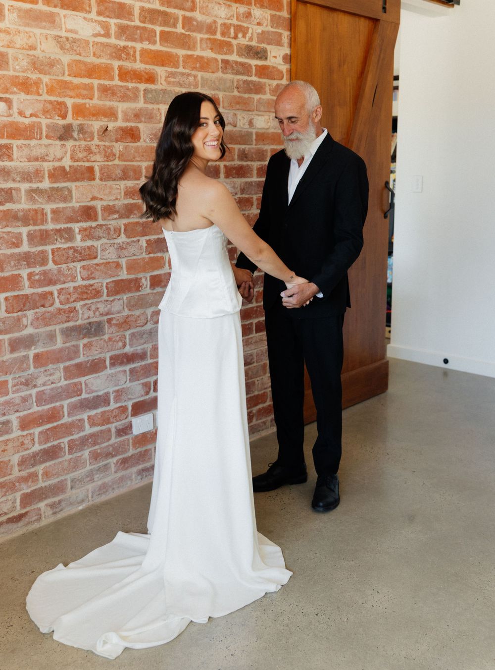 A couple sharing a special moment in a rustic venue with exposed brick walls and wooden door.