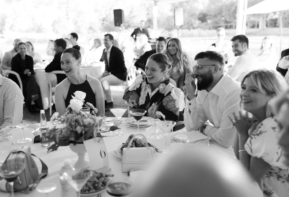 Reception guests sit at decorated dining tables at an elegant black and white wedding celebration.