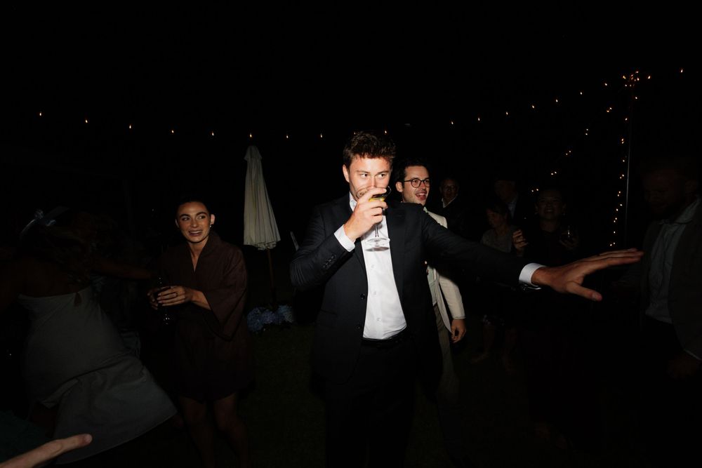 A darkly lit dance scene at an evening celebration with string lights overhead.