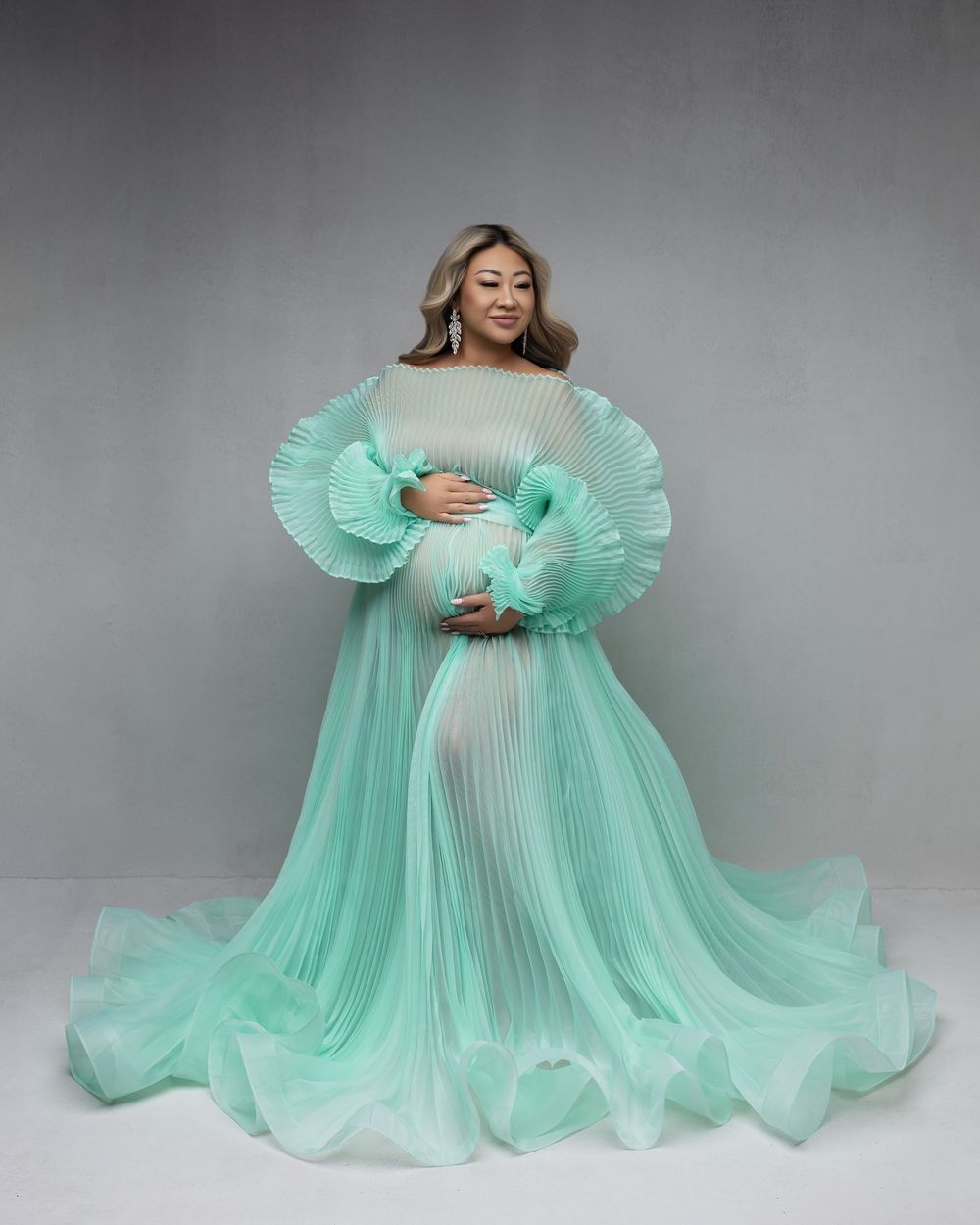 A flowing mint green tulle gown is shown from multiple angles against a gray backdrop.