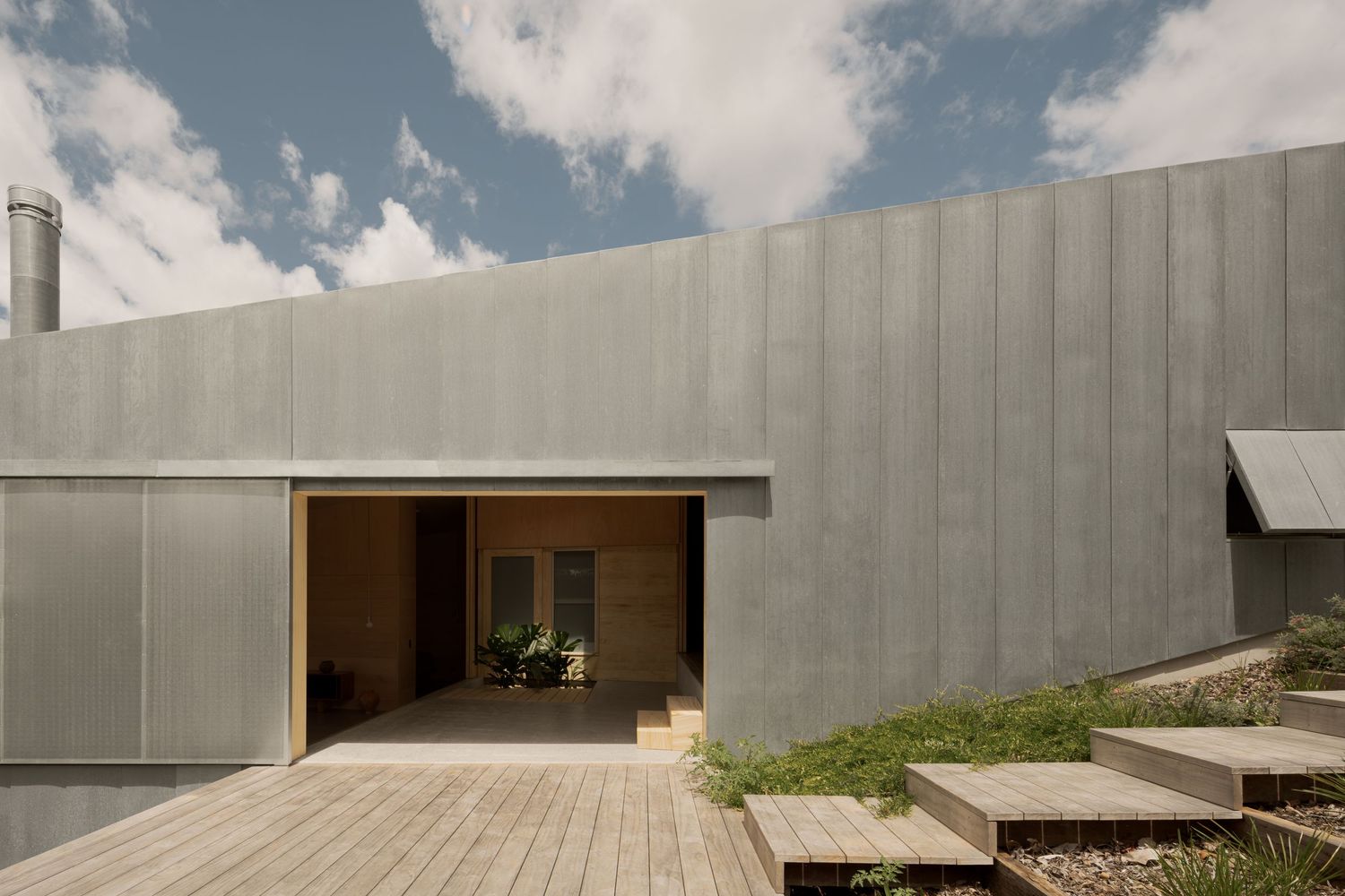 Contemporary concrete building exterior with wooden deck and stepped entrance.
