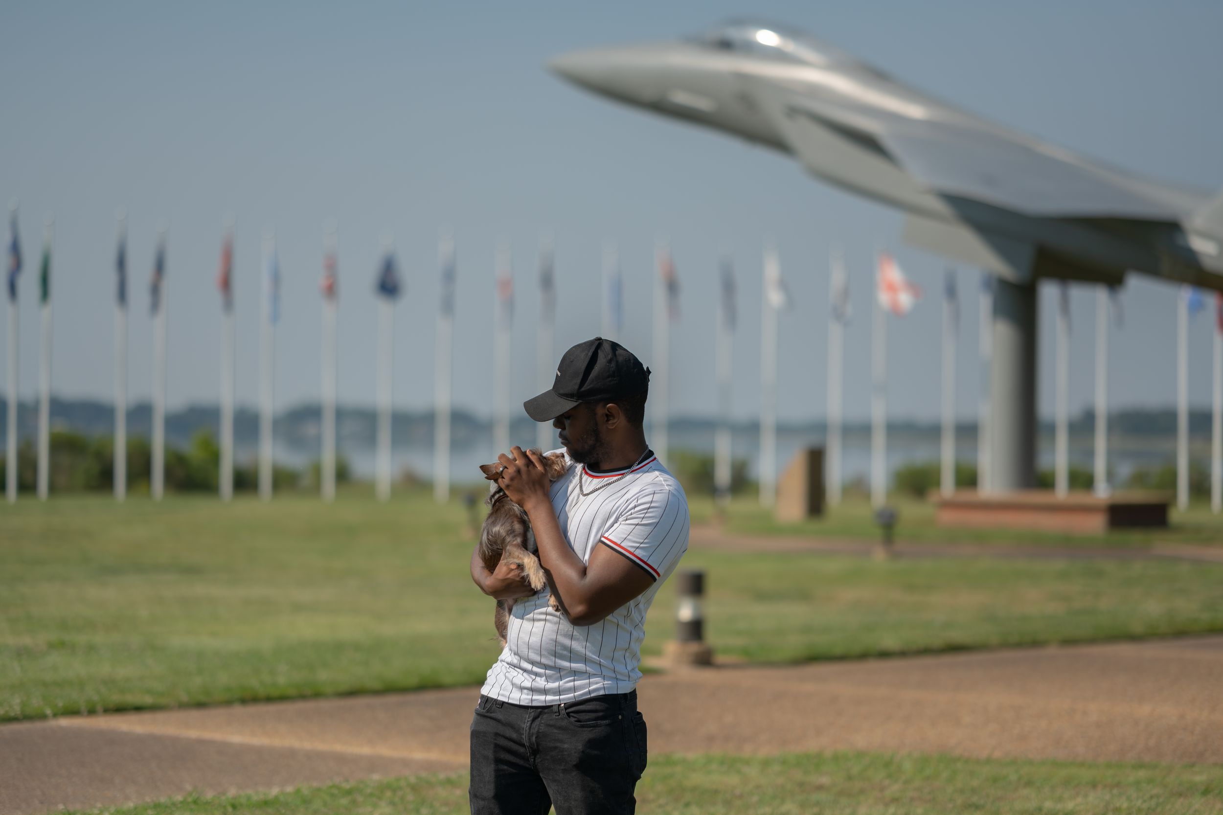 People enjoying a summer day at an outdoor aviation display with flags and a sleek aircraft model in the background.