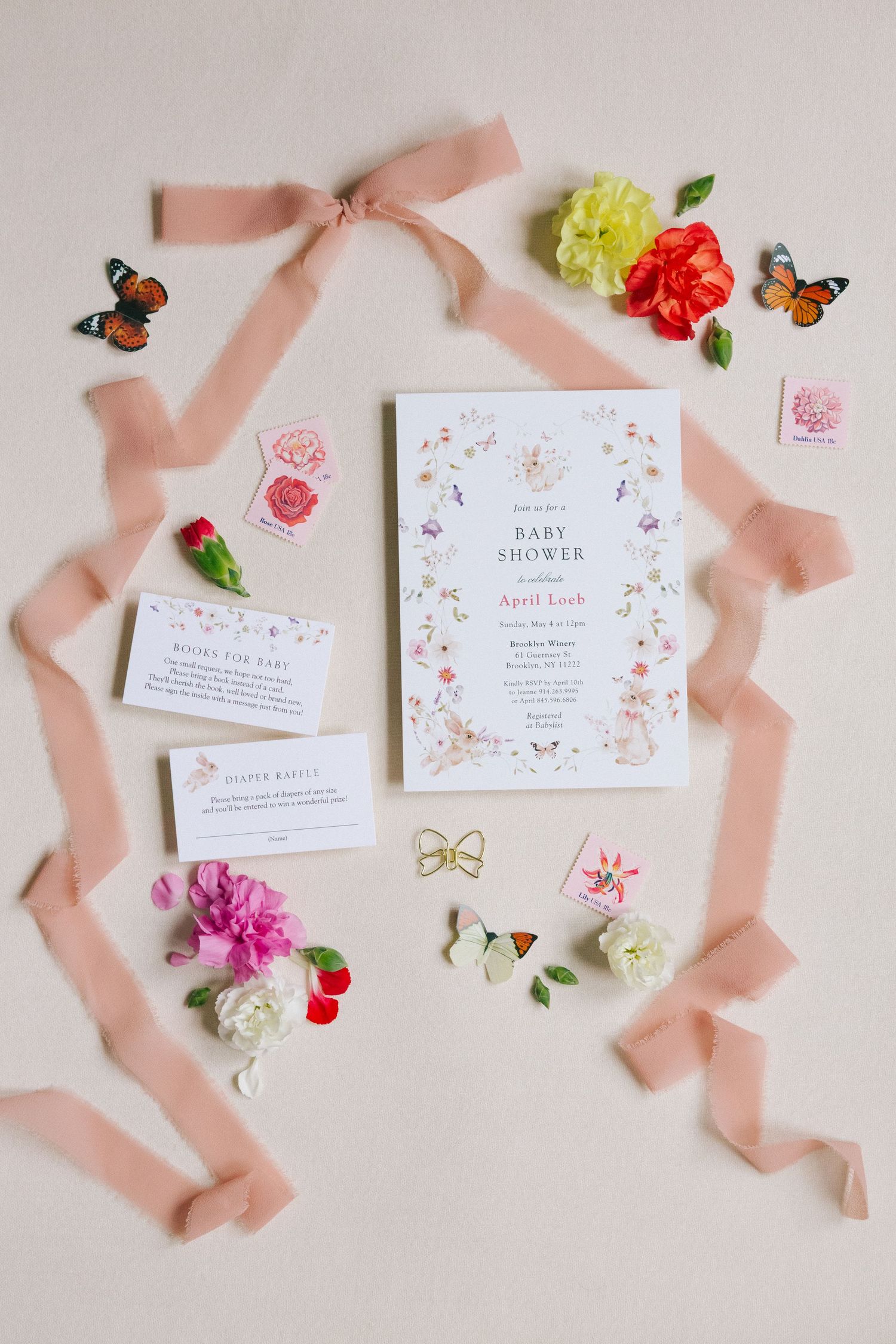 Elegant baby shower invitation flat lay with floral and butterfly accents, captured by NYC baby shower photographer Paula Brearley.