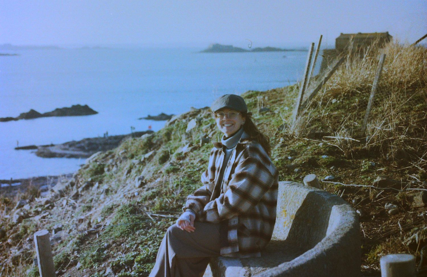 Photo argentique en couleur de Clélia Voisin assise sur un banc avec la mer en fond