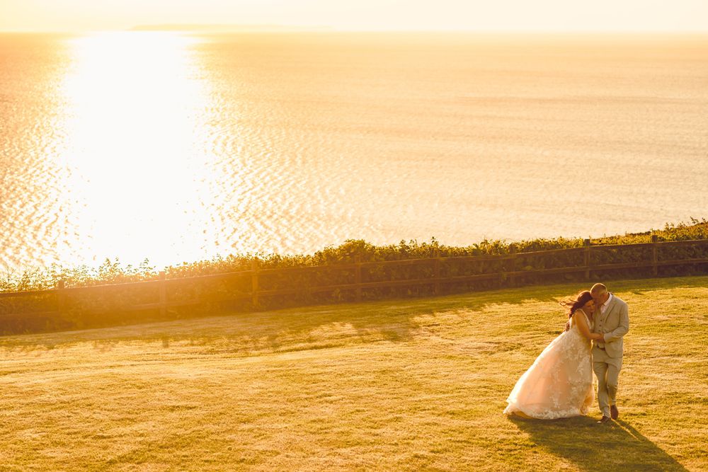 A bride and groom walk at sunset at Ocean Kave