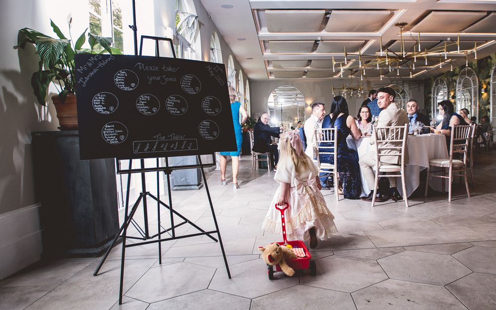 Young child playing with red wagon near event signage in modern venue space.