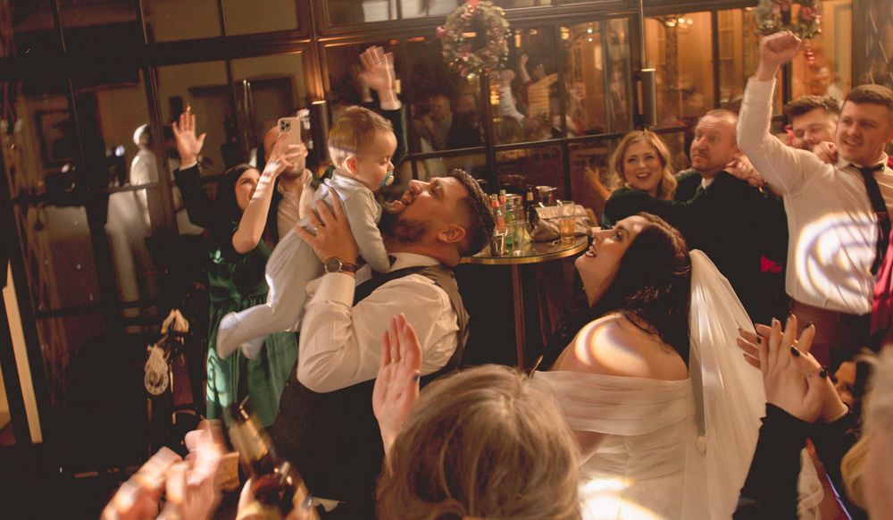 People dancing holding up a baby on the dancefloor at a wedding