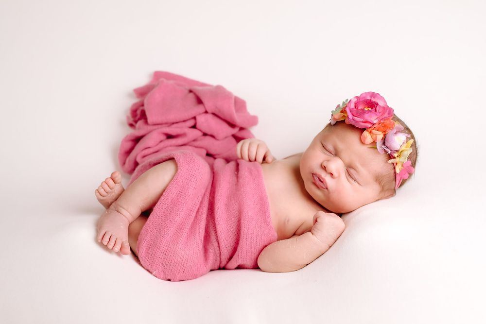 Buffalo In Home Newborn Session Photography. Newborn girl with pink swaddle blanket and floral headband