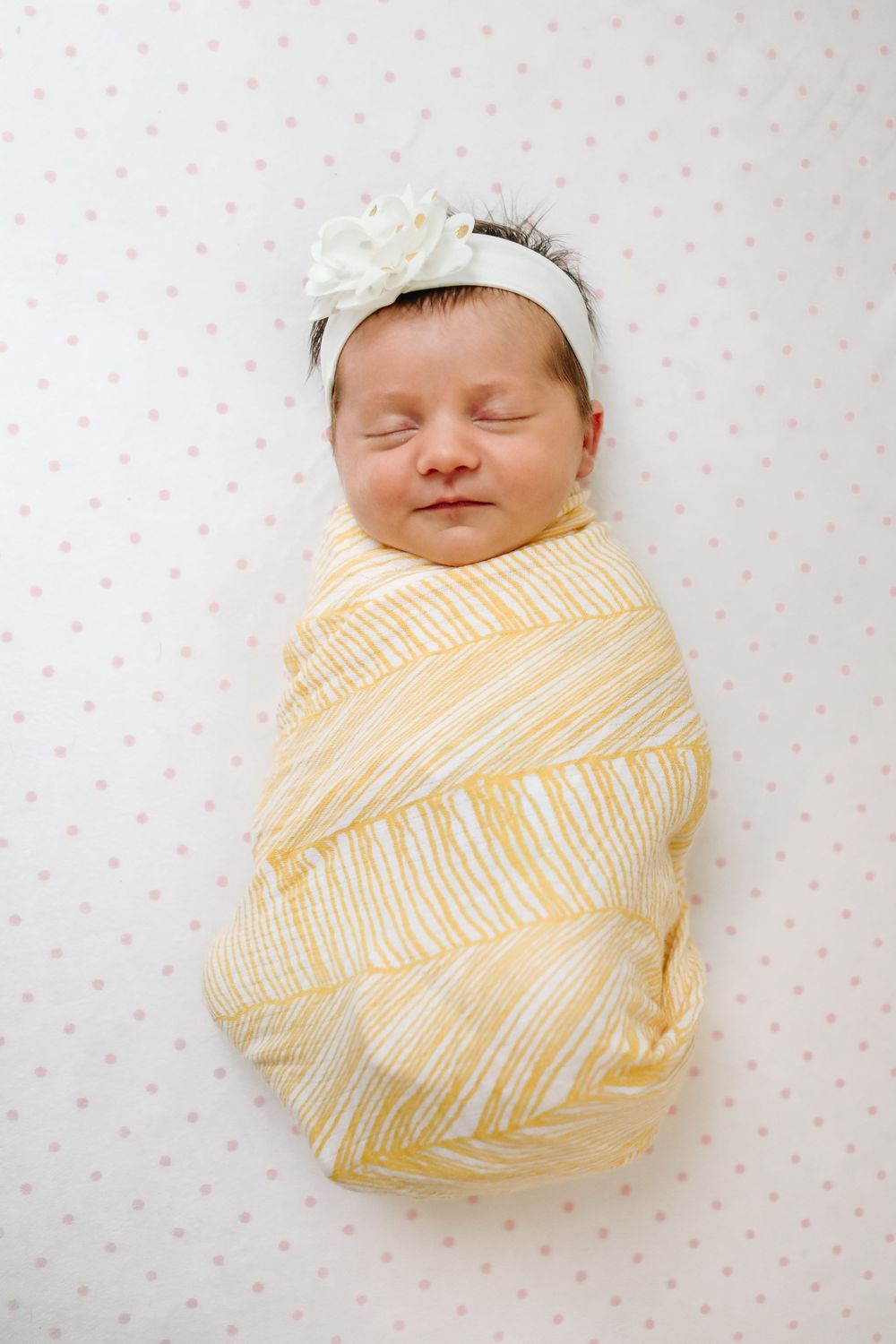 Buffalo In Home Newborn Session Photography. Newborn girl swaddled in yellow blanket with white floral headband.