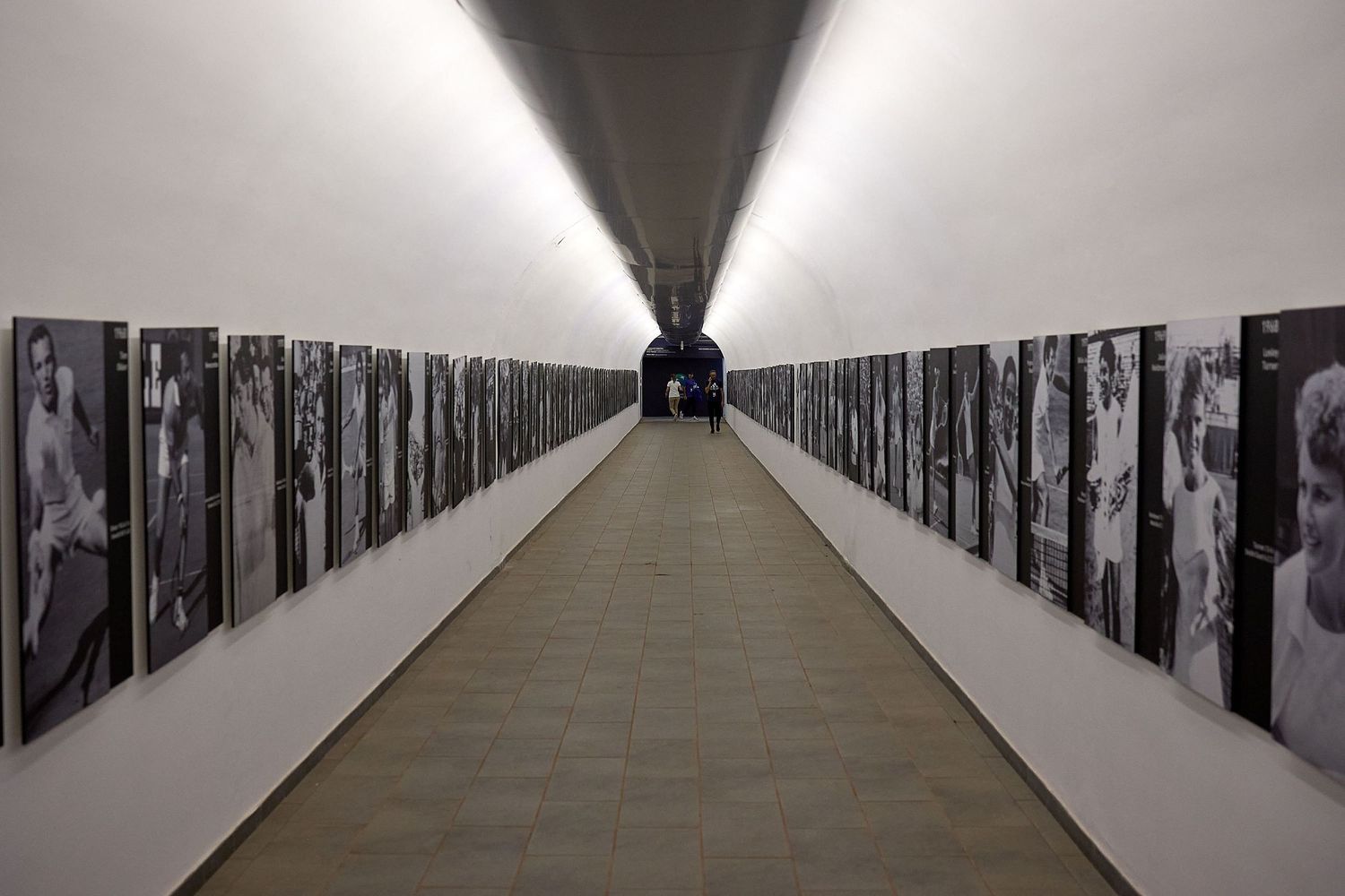 Long symmetrical hallway with black and white art installations on walls leading to distant vanishing point.