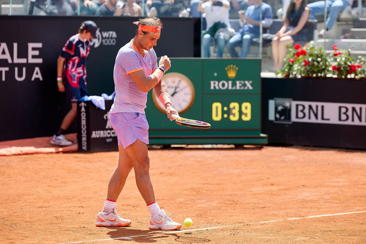 Tennis player in pink outfit moving across clay court during professional match.