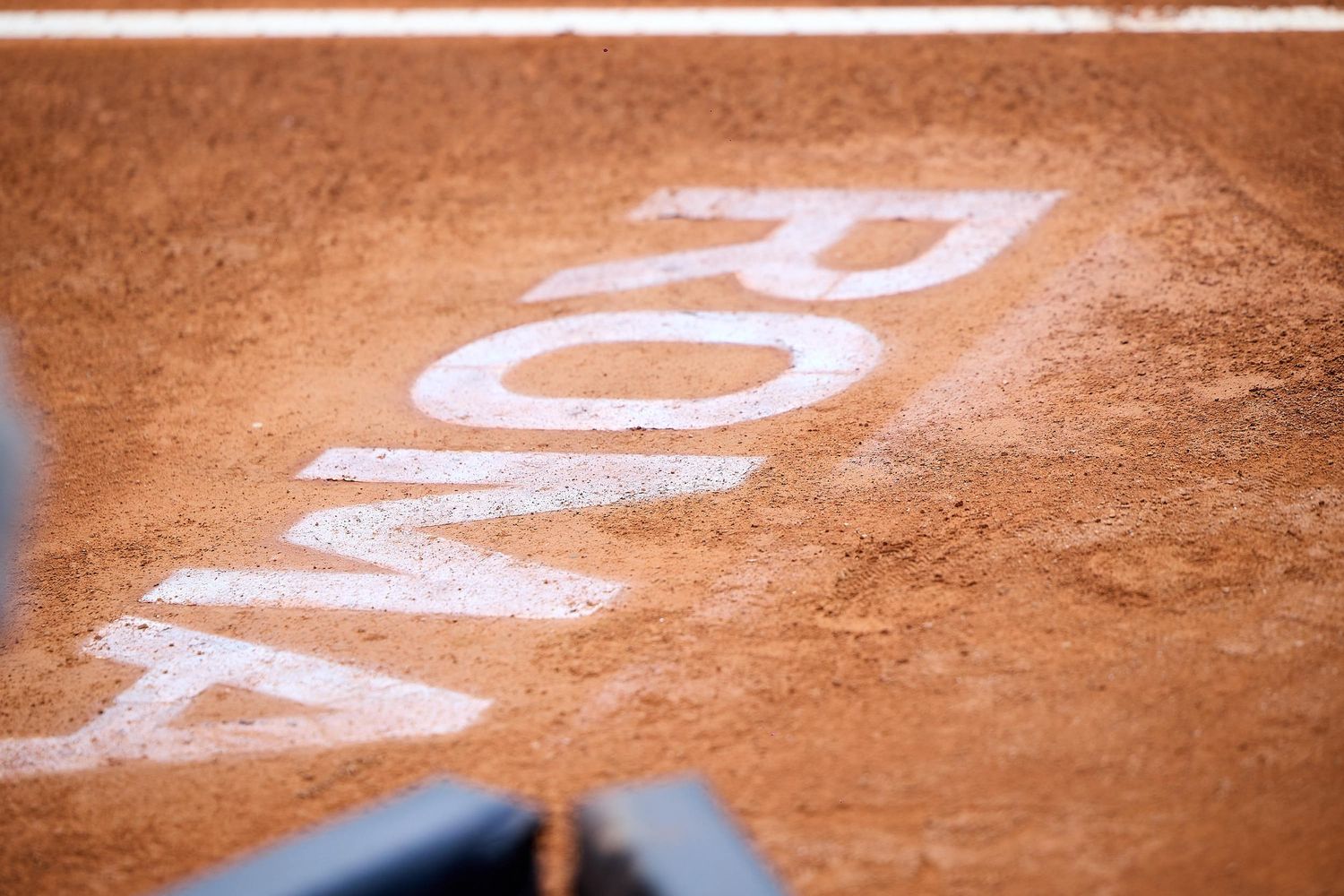 Close-up shot of text markings on clay tennis court surface.
