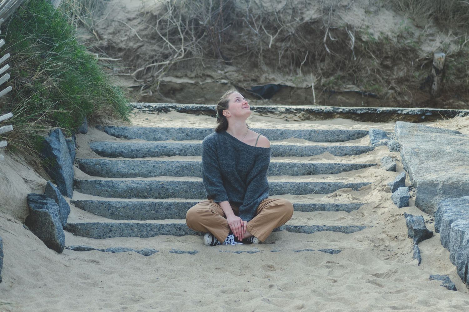 Photographie d'une femme assise sur des marches à la plage