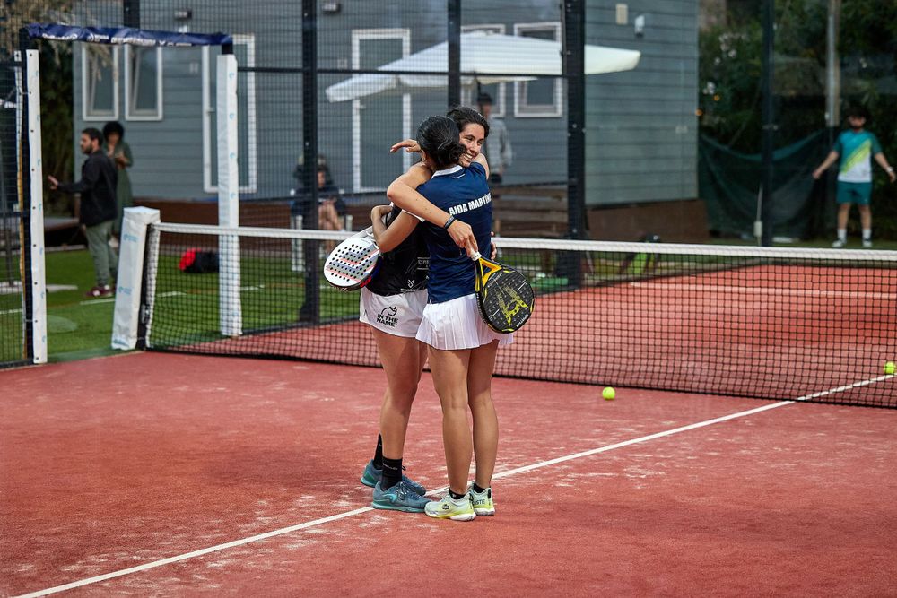 Two players embrace on clay tennis court after competitive match.
