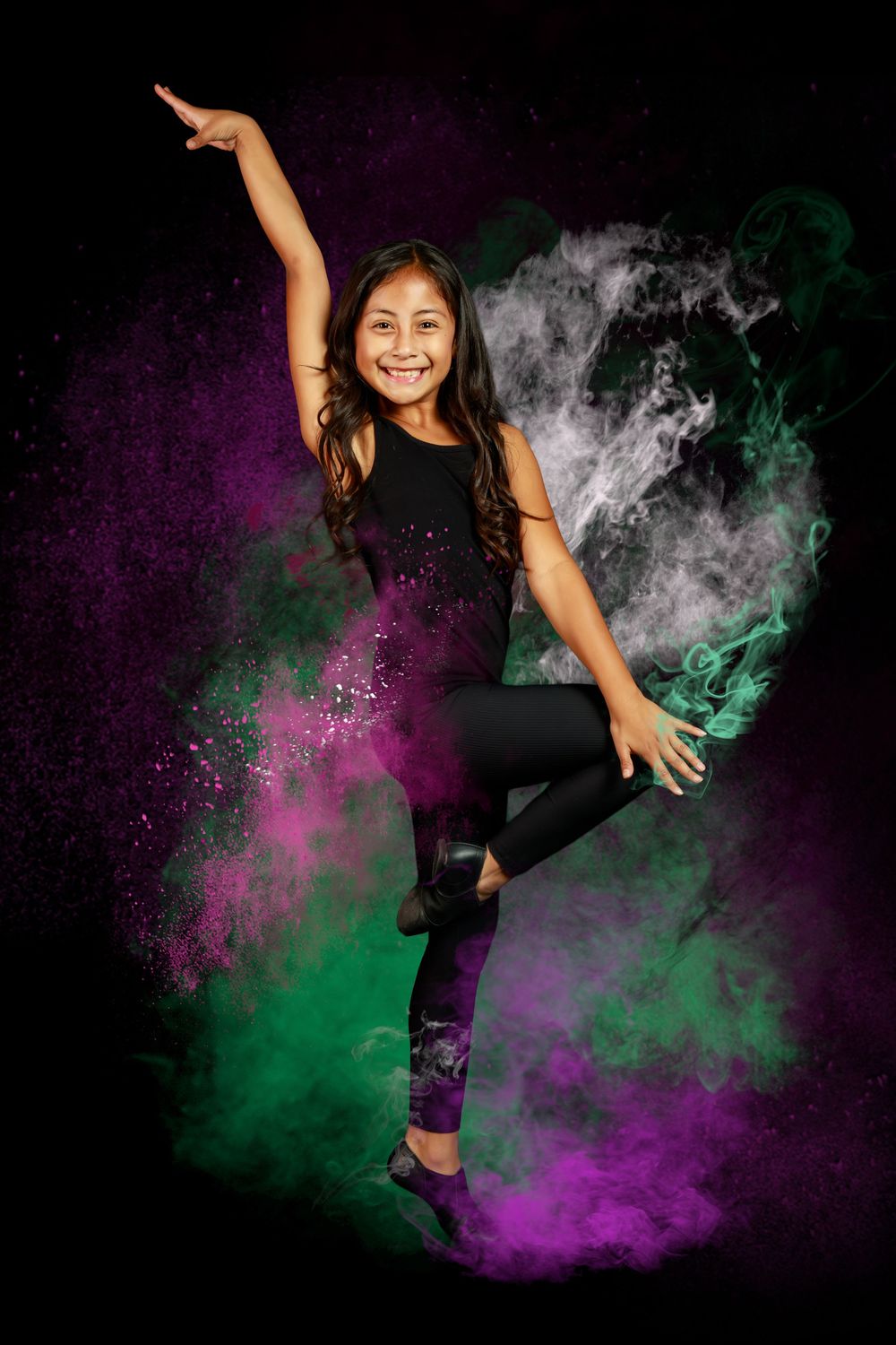 Young dancer in black and purple outfit performs graceful pose against swirling purple and green smoke background.