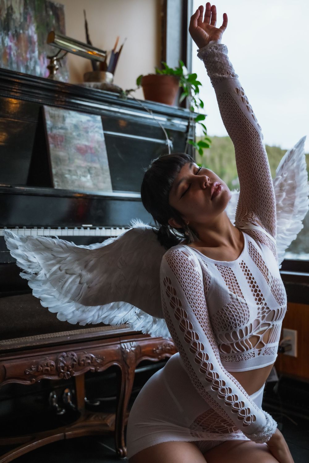 Boudoir artistique d’une femme en déguisement d’ange devant un piano