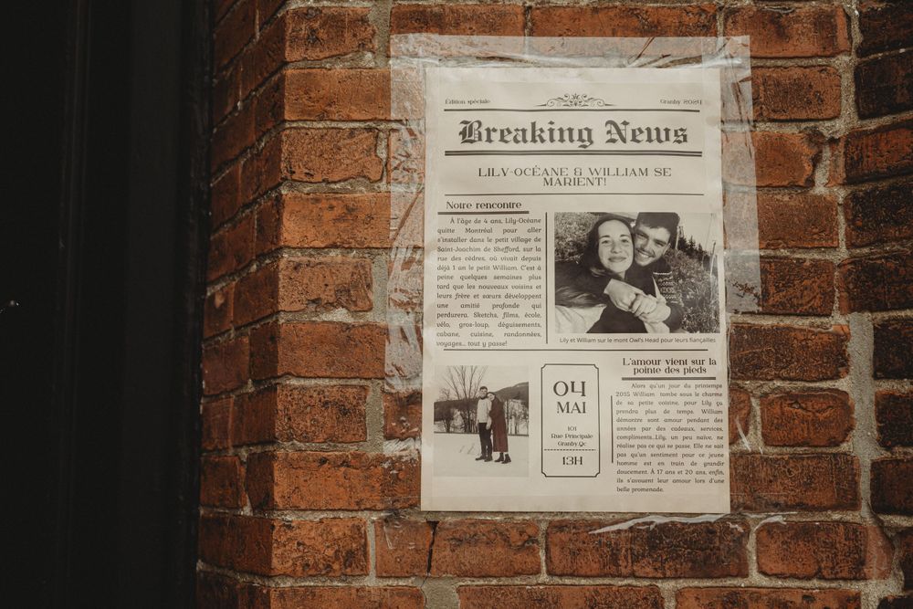 Vintage newspaper wedding announcement displayed on rustic brick wall.