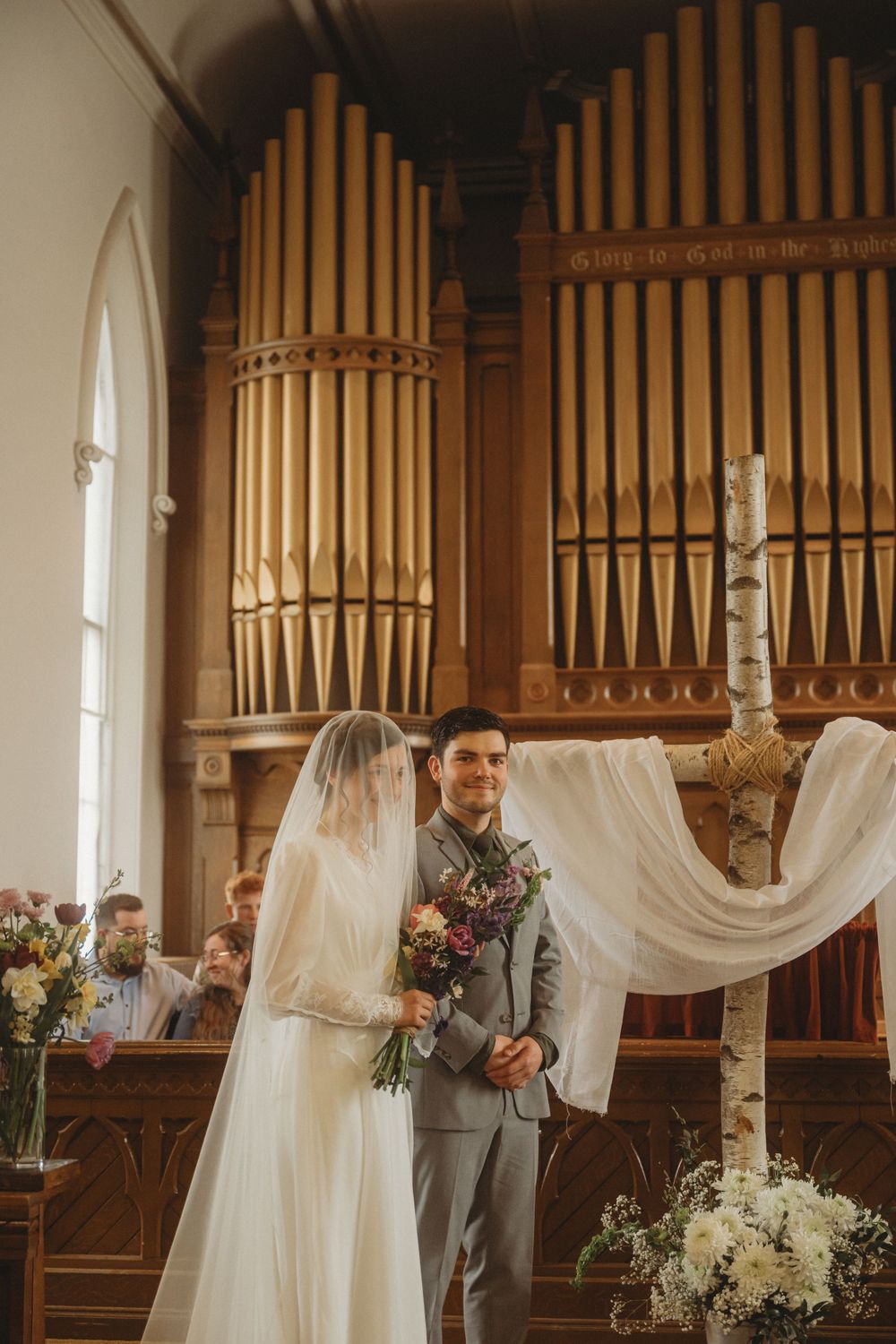A traditional church wedding ceremony takes place in front of ornate pipe organs.