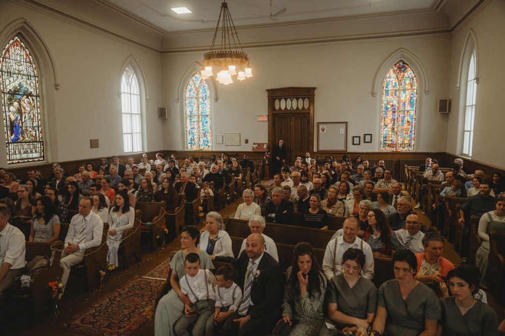 A crowded church sanctuary filled with wedding guests during a ceremony.