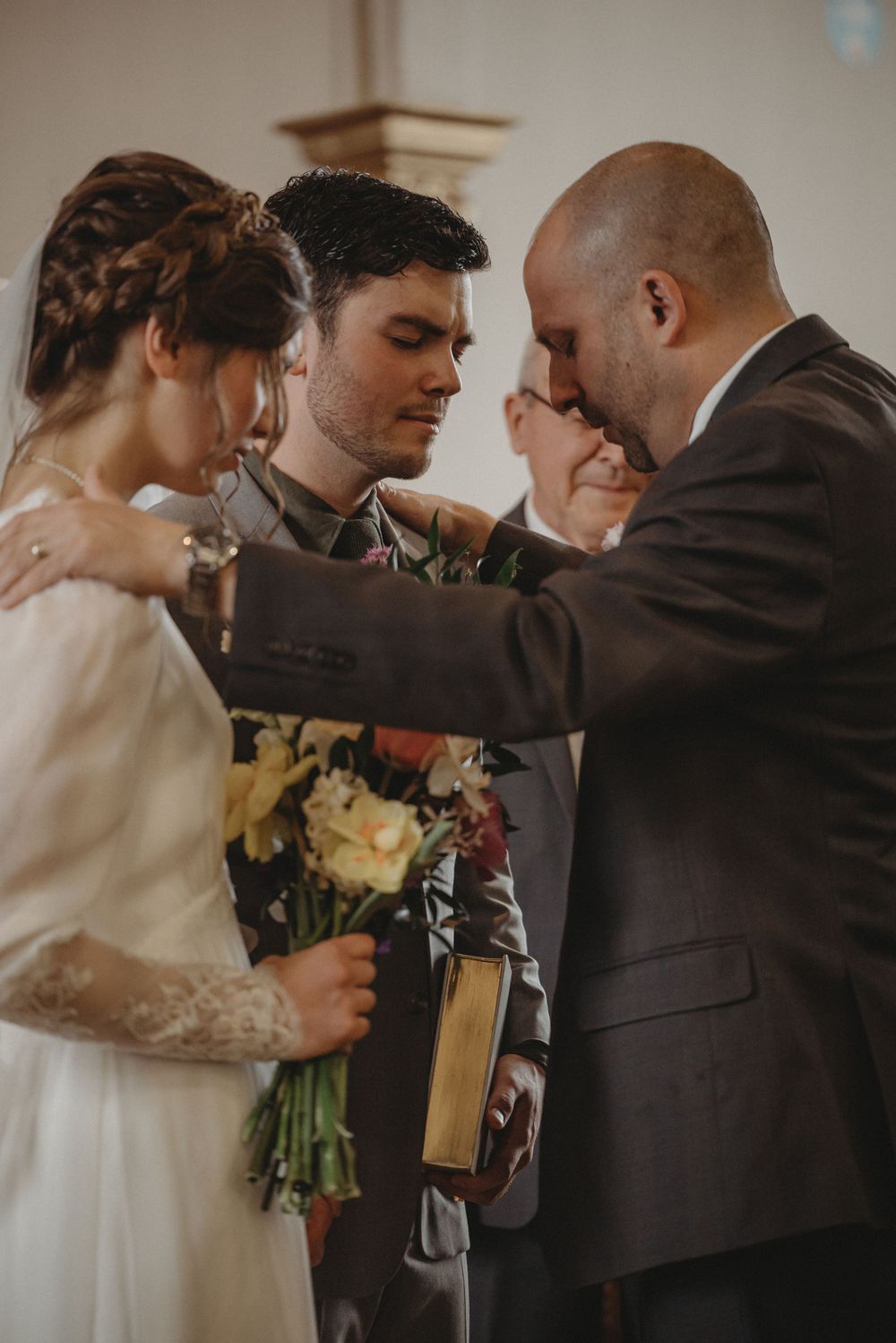 An intimate prayer moment during a wedding ceremony with bouquet and bible.