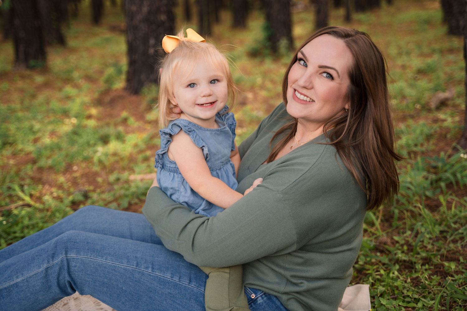 Parent and child in casual wear posing together in autumn forest setting.