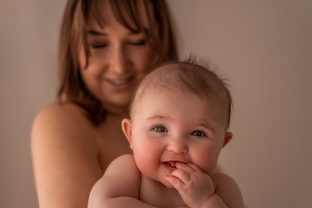 Sweet candid moment of a baby smiling while being held in warm lighting.