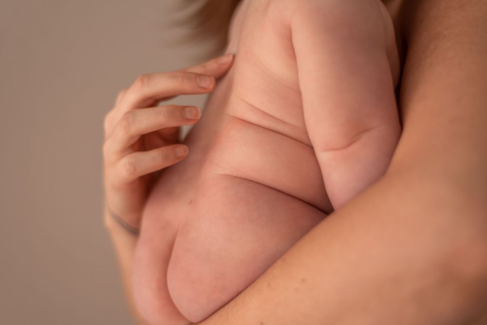 Close-up detail of gentle hands cradling baby's soft skin in warm lighting.